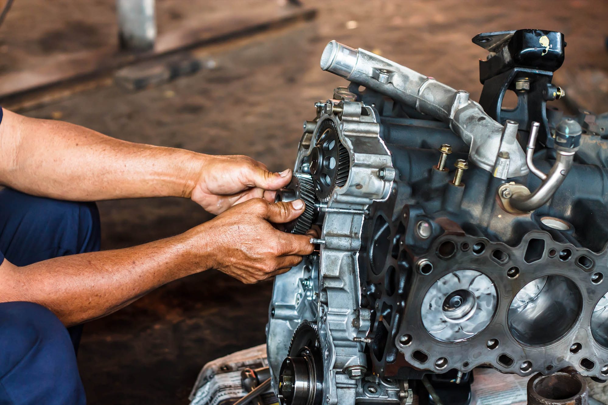 pic of a persons hands repairing a diesel engine