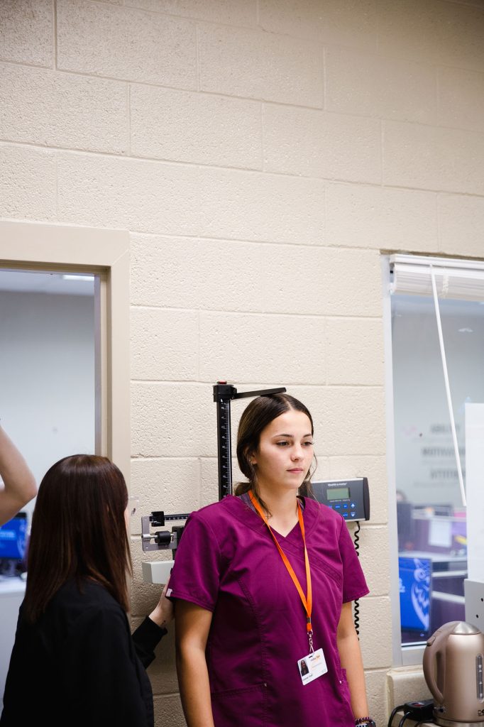 medical student taking a patients weight at Central Tech