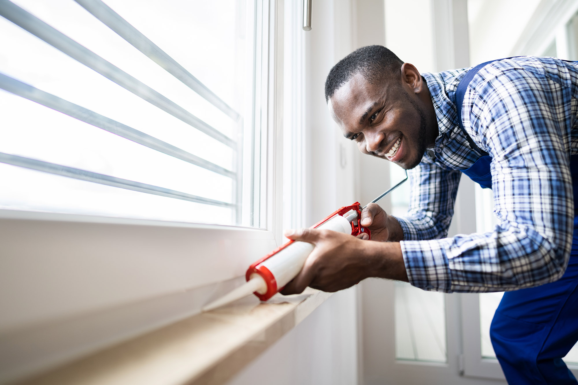 picture of a man caulking a window