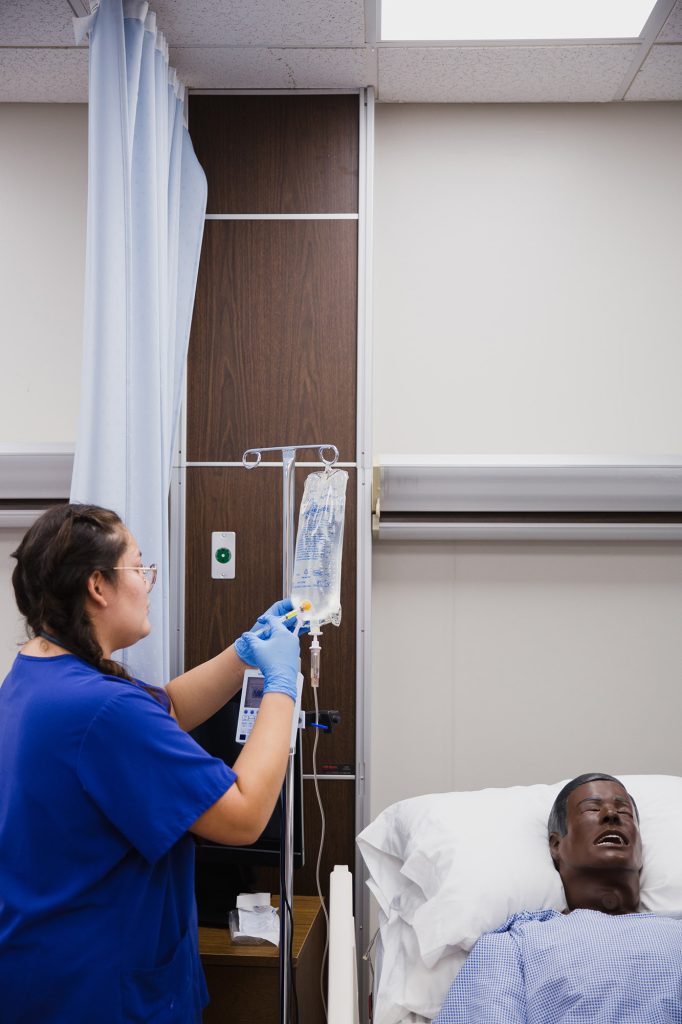 student administering an injection in an IV bag